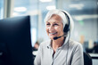 Call center agent with headset working on support hotline in office. Portrait of senior smiling agent in conversation with customer.
