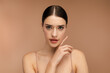 © Maria Vitkovska - Young woman with natural makeup posing and looking at camera Isolated on beige background. Skin care, beauty procedure, morning routine concept