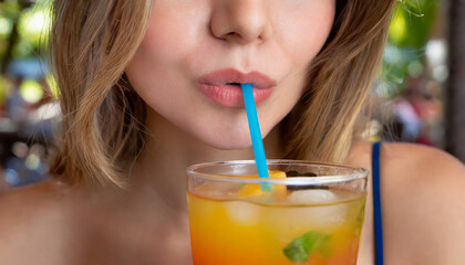 Wall Mural - Close-up of a woman's lips drinking a drink through a straw.