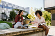 © Drobot Dean - Two cheerful female students studying together while sitting outdoors