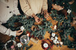© polinaloves - Happy women making Christmas wreath using natural pine branches and festive decorations.