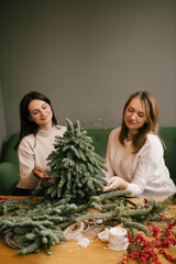 Wall Mural - Two women making Christmas tree using natural pine branches on a workshop.