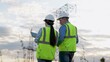 © SUPER FOX - Engineer demonstrates electric power distribution substation to colleague with tablet at sunset. Electricians inspect equipment with tablet at power generation plant with transmission lines in field