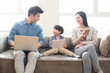 © Blue Jean Images - Happy young family using laptop and digital tablet
