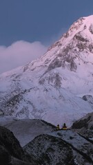 Wall Mural - Stepantsminda, Gergeti, Georgia. Mount Kazbek Covered Snow In Winter Sunrise. Morning Dawn Colored Top Of Mountain In Pink Colors. Awesome Winter Georgian Nature Landscape. Time Lapse Timelapse .