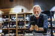 © Jelena Stanojkovic - Mature male Caucasian consumer checking information on mobile phone in grocery. Man using cellphone while shopping bottle of wine in the grocery store.