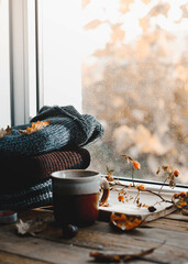 Large Cup of cappuccino on vintage brown background. Autumn, fall leaves, hot steaming cup of coffee and a warm scarf on wooden table background. Seasonal, morning coffee, Sunday relaxing and still l