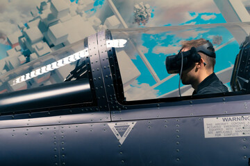 Wall Mural - boy sitting in flight simulator of military plane wearing virtual reality glasses during flight entertainment