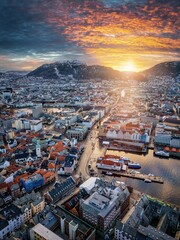 Wall Mural - Aerial winter sunrise view of the cityscape of Bergen, Norway, with golden sunlight hitting the snow capped mountains
