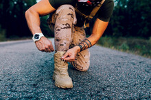 Crop Anonymous Mature Male Commando Tying Shoelace While Kneeling On Road