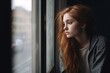 © Irina - A sad young woman is sitting by the window Alone, The time of epidemics, communication problems. Covid.