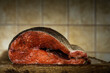 raw gutted rainbow trout with spices without a head lies front cross-cut on a cutting board on a soft beige kitchen tile background. close-up photo of food with copy space