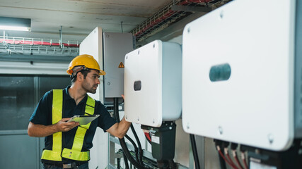 Technician Engineering setting inverter solar panel in electrical room. Service engineer installing solar cell on the roof of factory. Clean and Renewable energy concept.