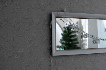 Wall Mural - A mirror decorated with a garland and a reflection of a Christmas tree