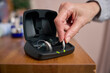 Close Up Of Person Picking Up Wireless Hearing Aid Or Device From Charging Case At Home