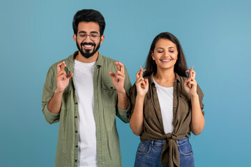 Wall Mural - Excited millennial indian couple holding crossed fingers