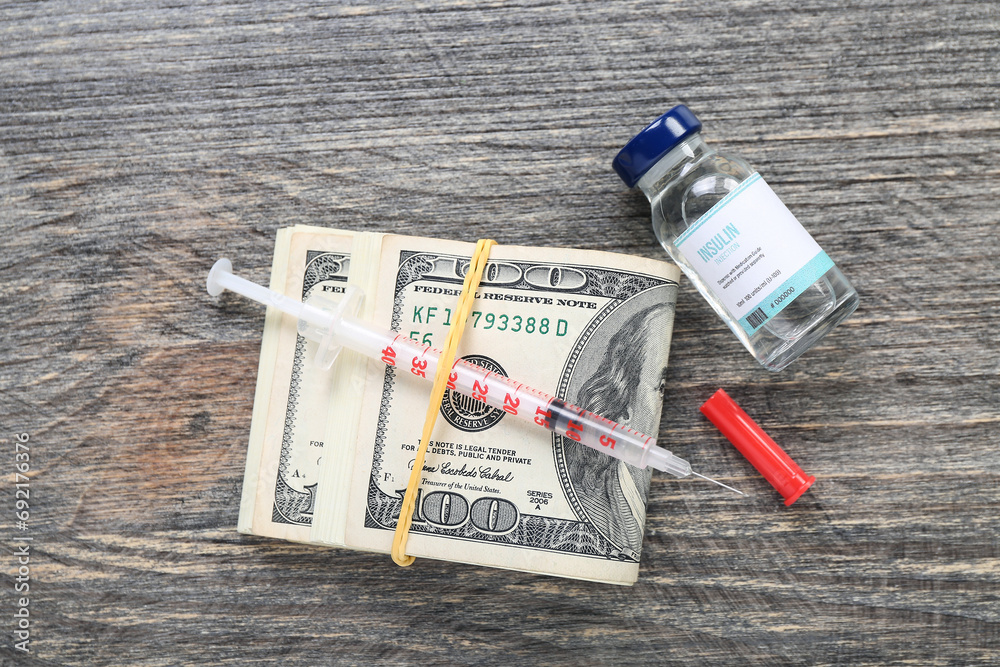 Insulin with syringe and money on dark wooden background. Expensive medicine concept