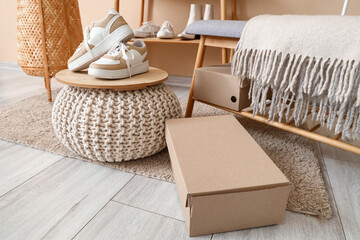 Wall Mural - Pouf with stylish female sneakers,  cardboard box and bench in boutique, closeup