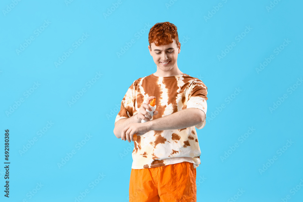 Young man applying sunscreen cream on blue background