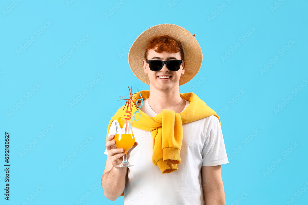 Young man with summer cocktail on blue background