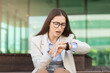 Sad stressed businesswoman checks watch with concerned expression, depicting urgency