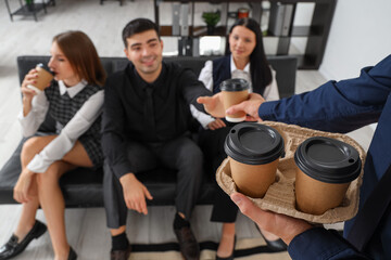 Wall Mural - Young man giving coffee to his colleagues in office, closeup