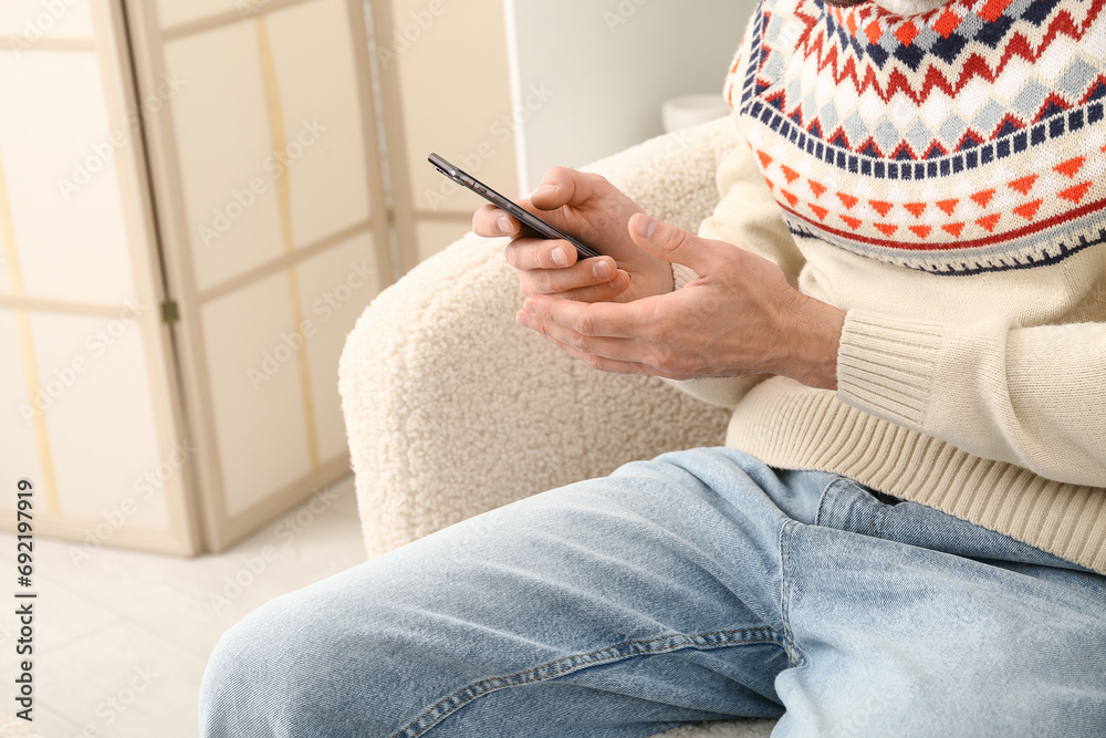 Handsome man using mobile phone on sofa in living room, closeup