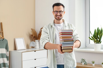 Wall Mural - Handsome man with stack of books in living room
