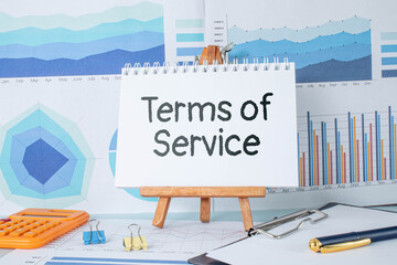 Poster - Terms of Service text on a yellow sticker. notepads on a wooden background near a potted plan