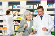 © JackF - At pharmacy, male chemist consulting mature woman client and shows cream to moisturize of aging skin and convinces doubter to purchase mini version of care product.