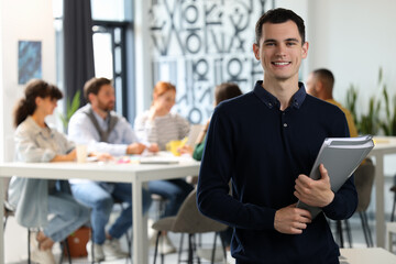 Canvas Print - Team of employees working together in office. Happy man with folders indoors, space for text