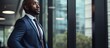 © AkuAku - African businessman thinking and brainstorming in office, professional male CEO planning by window in workplace.