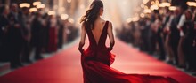 Woman In Elegant Red Gown Walking Down Celebrity Red Carpet Event. Fashion And Glamour.