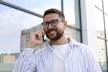 Sticker - Handsome bearded man in glasses talking on phone outdoors