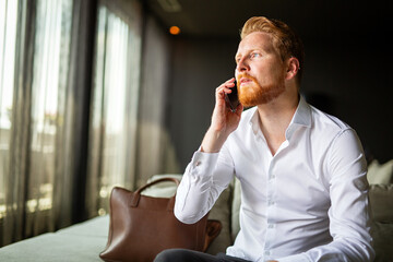 Wall Mural - Portrait of success business man talking on mobile phone while sitting in the hotel room