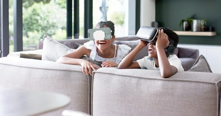 Wall Mural - happy african american brother and sister in vr headsets on sofa, copy space, slow motion