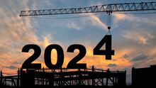 Crane Lifting Number 4 Come Down To 2024 , Prepare For Welcome Beginning New Year 2024 With Silhouette Construction Site , Sunrise Sky At Background For Start And Reach New Goals For Year 2024.