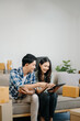 © Nuttapong punna - Young attractive couple man and woman use tablet and smartphone online shopping furniture decorate house with carton package move in new house. ฃ.