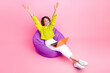 Full length photo of pretty excited girl dressed neon sweater sitting bean bag online studying modern gadget isolated pink color background