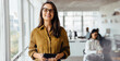 © (JLco) Julia Amaral - Happy business woman holding a tablet while standing in an office