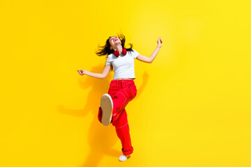 Sticker - Full length photo of positive cool lady wear white t-shirt earphones walking having disco fun flying hair isolated yellow color background