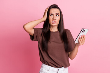 Poster - Portrait of young unsatisfied lady grin teeth using smartphone touch head look empty space oops failed isolated on pink color background