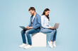 © Prostock-studio - Focused couple on cube using laptops in denim attire