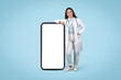 © Prostock-studio - Friendly woman doctor leaning on a blank mobile screen