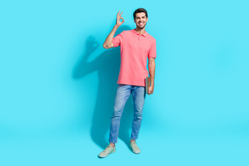 Poster - Full body size photo of young recruiter guy wear pink t shirt denim jeans shows okey sign holding netbook isolated on blue color background