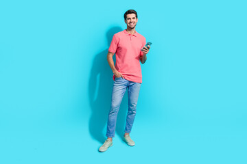 Wall Mural - Full body photo of young handsome man wearing pink t shirt using smartphone sending proposition isolated on aquamarine color background