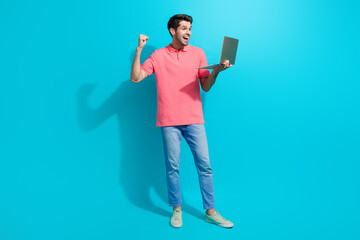 Aufkleber - Photo of young successful businessman raised fist up using macbook pro and enjoying fast montage isolated on cyan color background