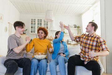 Wall Mural - Group of friends watching sport match soccer football game on tv. Happy football fans celebrating victory at home. Friendship sports entertainment concept. Diverse buddies having fun together at home