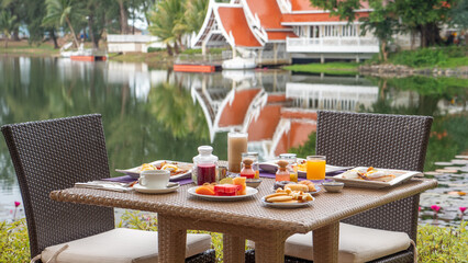 Wall Mural - Outdoor breakfast setup at lakeside resort with reflection of nature. Travel and leisure.