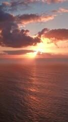 Wall Mural - Flying to setting sun in dramatic clouds over Atlantic ocean. Vertical video